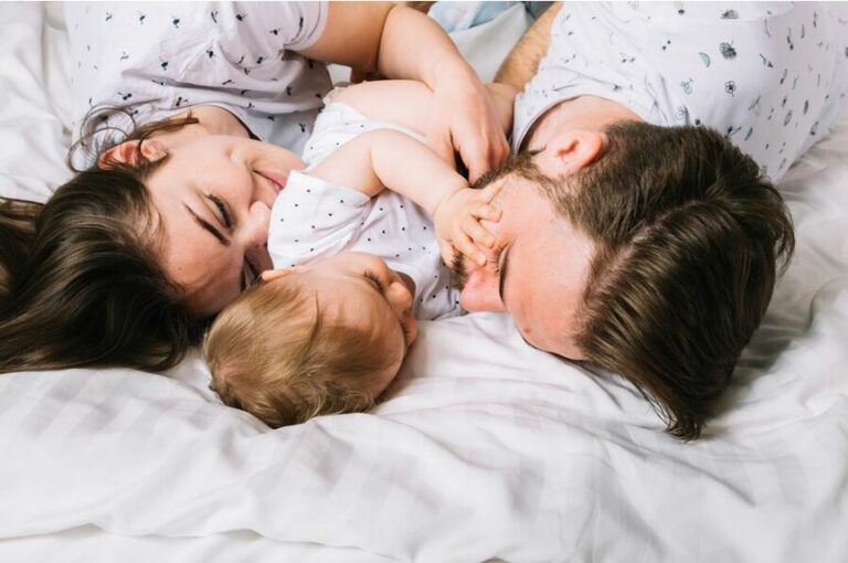 Photos de jeunes parents avec leur bebe allongés dans le lit le matin